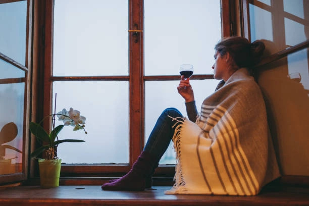 A woman looking out a farmhouse window in winter