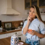 Woman standing in kitchen lost in thought