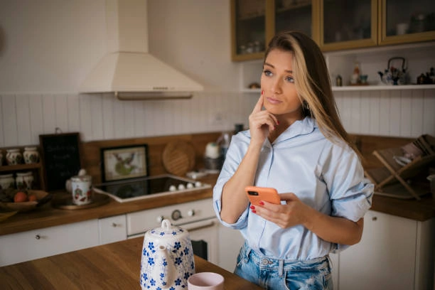 Woman standing in kitchen lost in thought