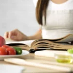 Woman reading cookbook at rustic kitchen table