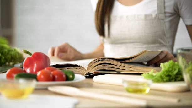 Woman reading cookbook at rustic kitchen table